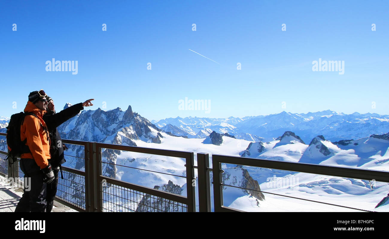 Skiers admire the breathtaking view of the Mont Blanc massif, from the heights of the Aguille du Midi Stock Photo