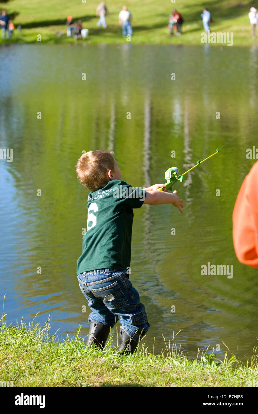 A young boy casting his fishing pole while fishing in a pond during a