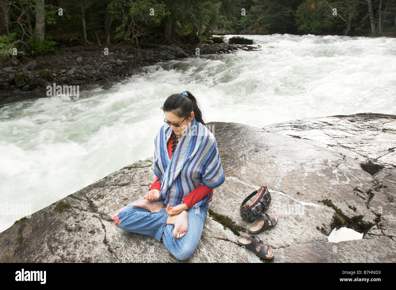 A woman does yoga near a raging river near Whistler British Columbia Canada Stock Photo