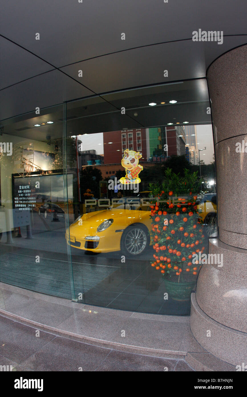 Porsche Dealership Window in China with Chinese New Year Decorations and orange tree in show room next to Yellow Carrera Stock Photo