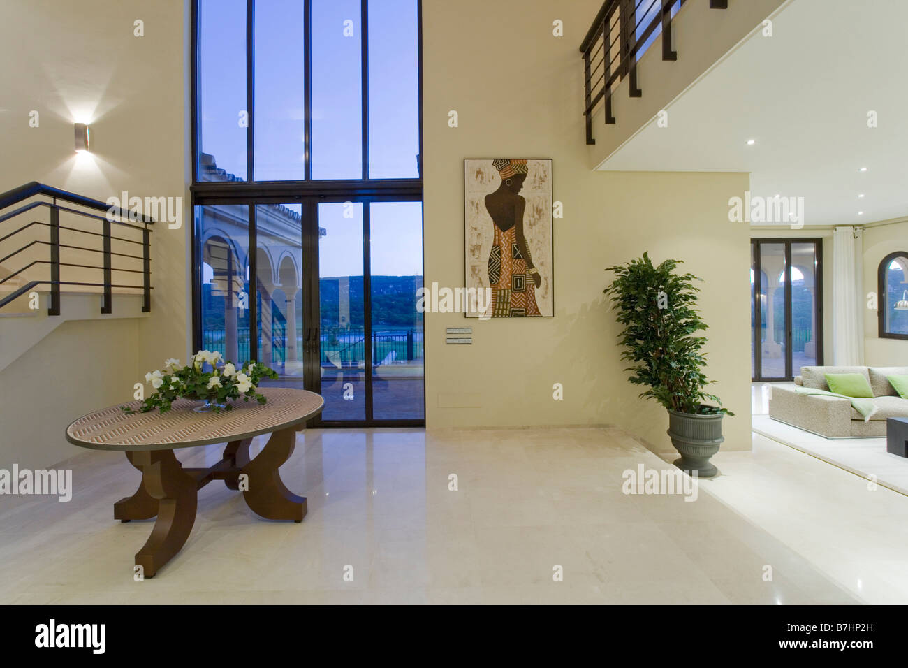 Circular table and marble floor in large openplan hall with floor to ceiling windows in modern Spanish holiday villa Stock Photo