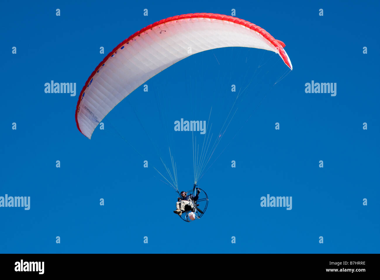 a powered paraglider pilot in flight against a clear blue sky Stock Photo Alamy