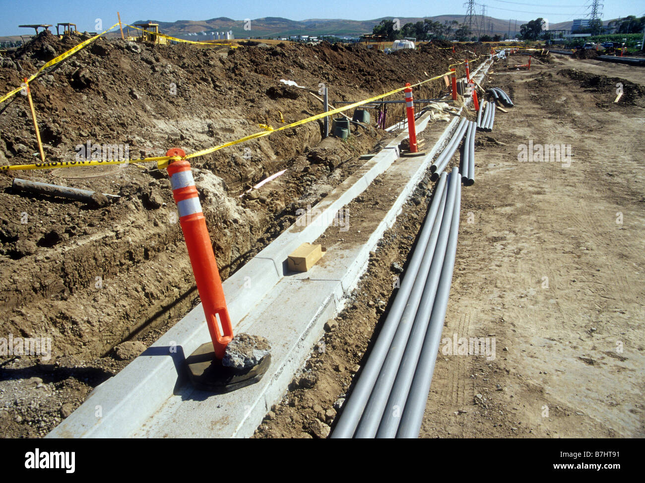 Cement curb under construction with plastic pipes to be buried Stock