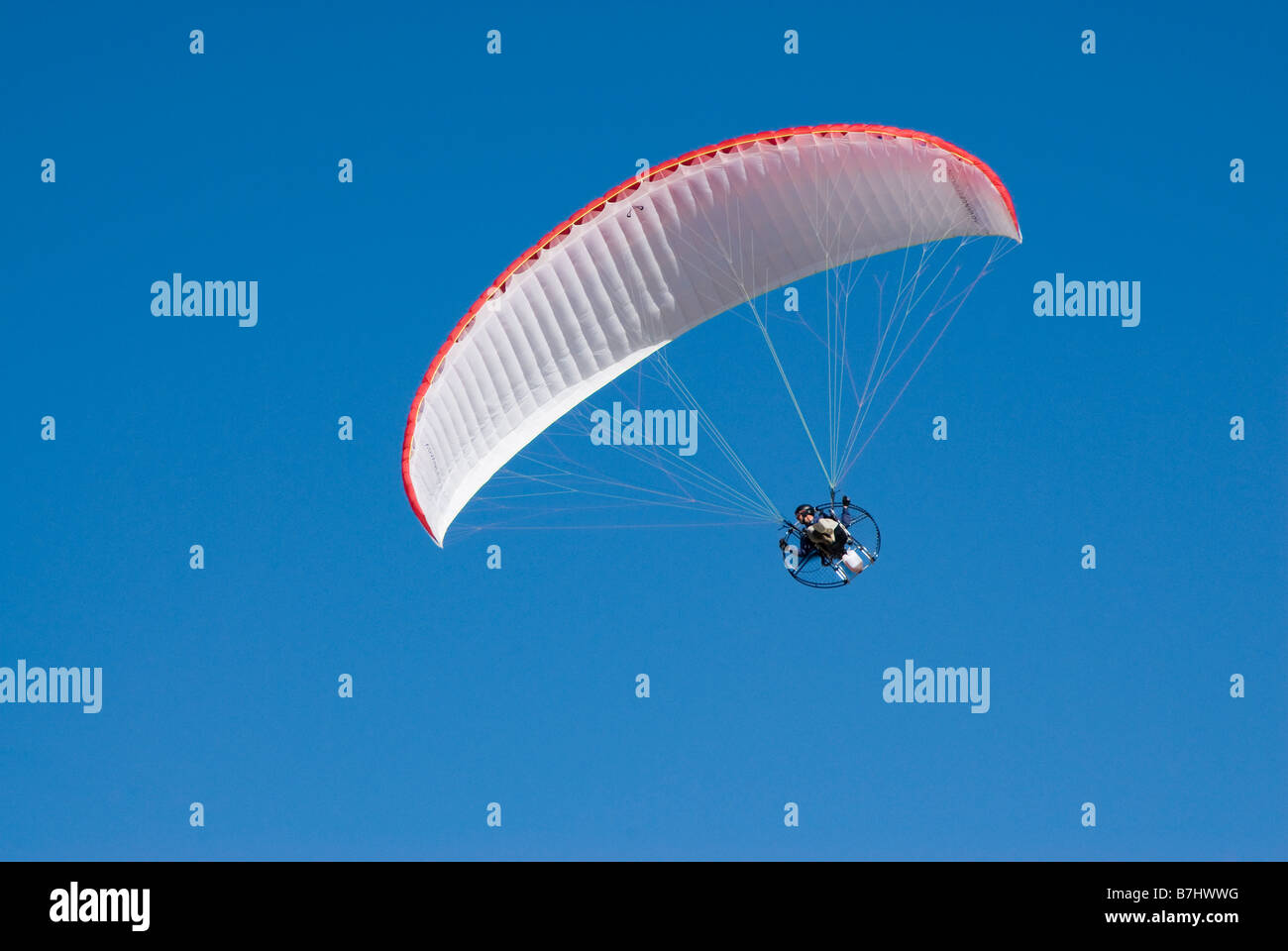 a powered paraglider in flight against a clear blue sky Stock Photo Alamy
