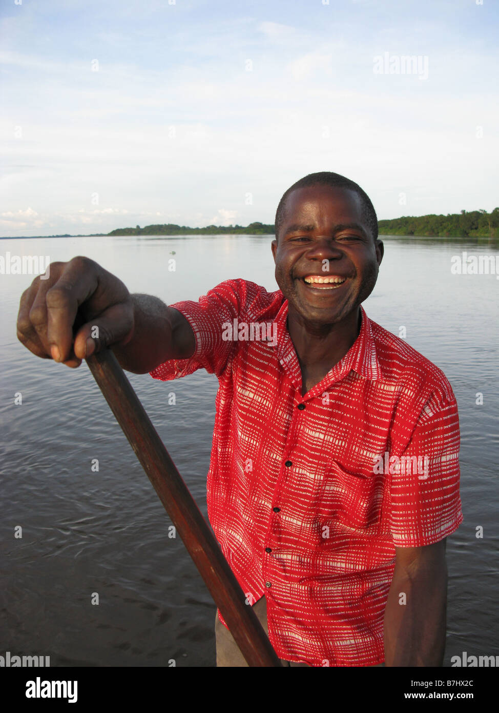 Portrait of friendly smiling Lingala fisherman paddling dugout canoe on the River Congo Democratic Republic of Congo Stock Photo
