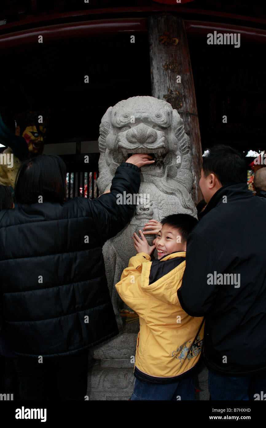 CHinese people placing hands all over stone lion at the 1700 year old Guangxiaosi Buddhist temple Stock Photo