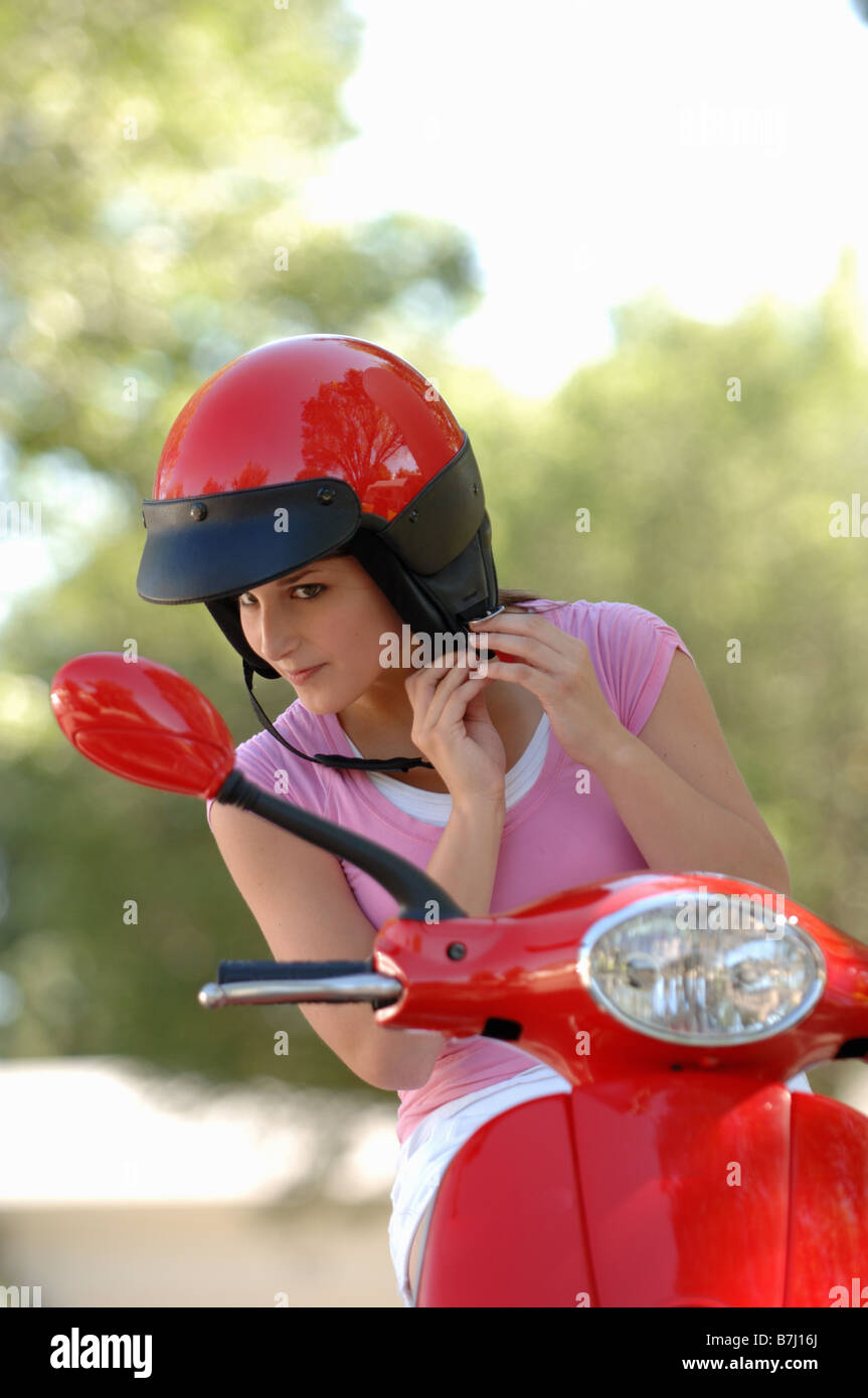 Young girl fastening helmet on red vespa motor scooter, Regina, Saskatchewan Stock Photo