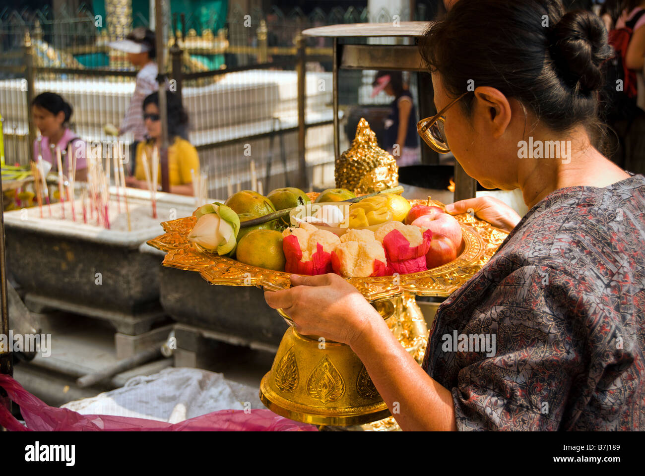 Thai woman making fruit and flower offering - Wat Phra Kaew and the Grand Palace in central Bangkok Thailand Stock Photo
