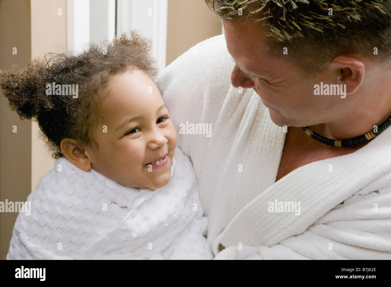 Caucasian dad snuggling with his 3 year old Mulatto girl. Stock Photo