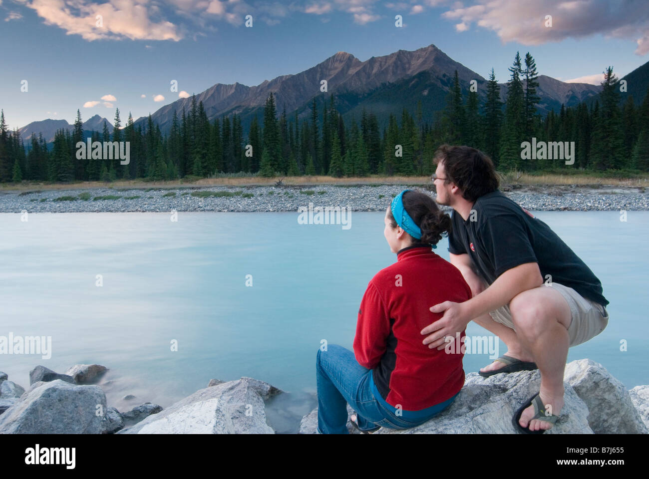 A couple enjoys the sunset from the banks of The Kootenay River in Kootenay National Park Stock Photo