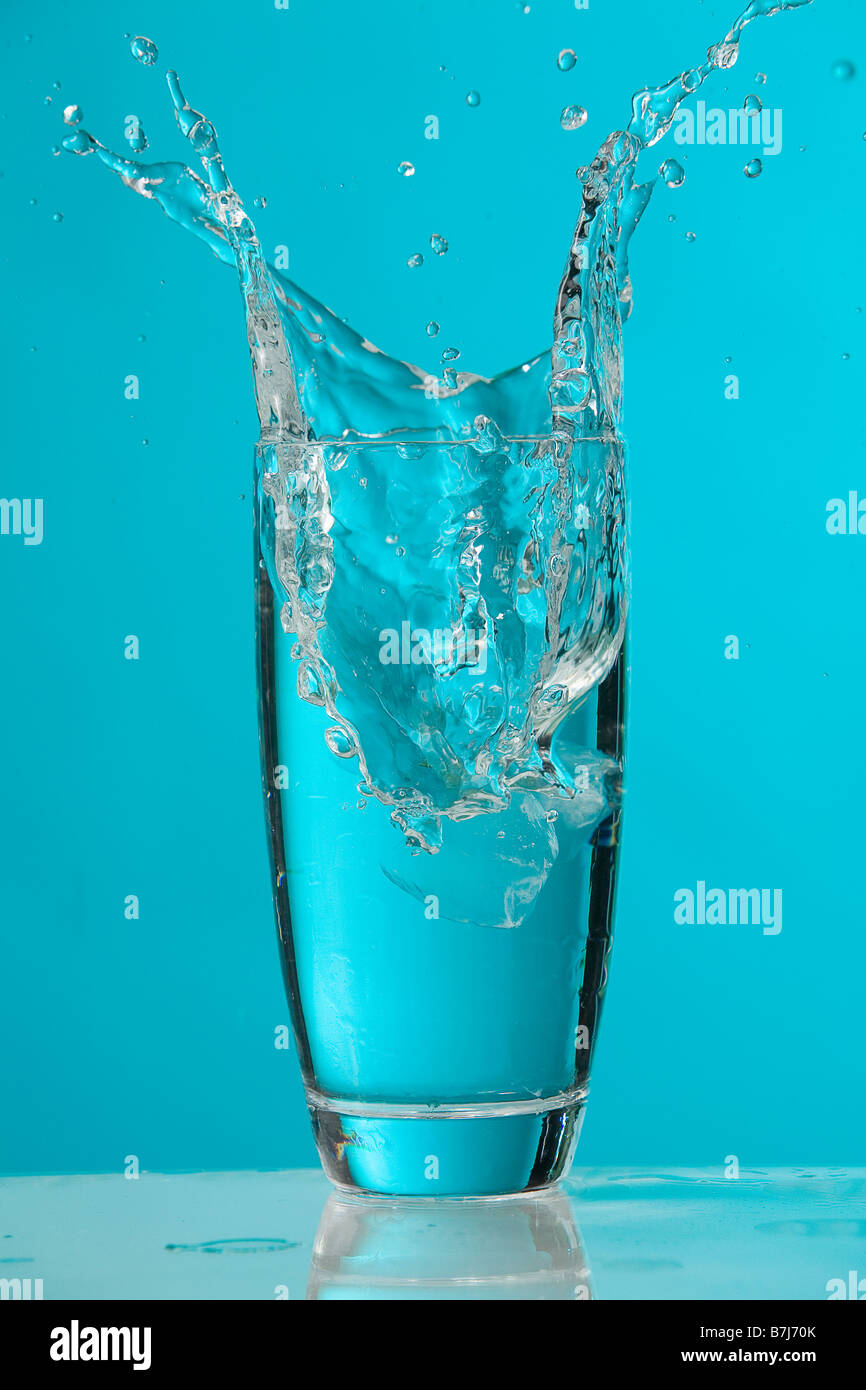 Water splash as ice cube drops into glass of water Stock Photo - Alamy