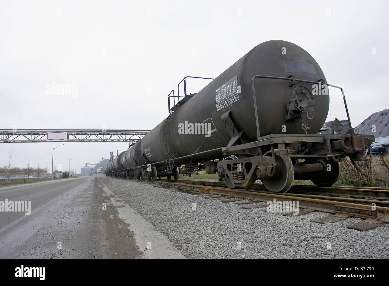 Train alongside empty road in industrial setting, Hamilton, Ontario. Stock Photo