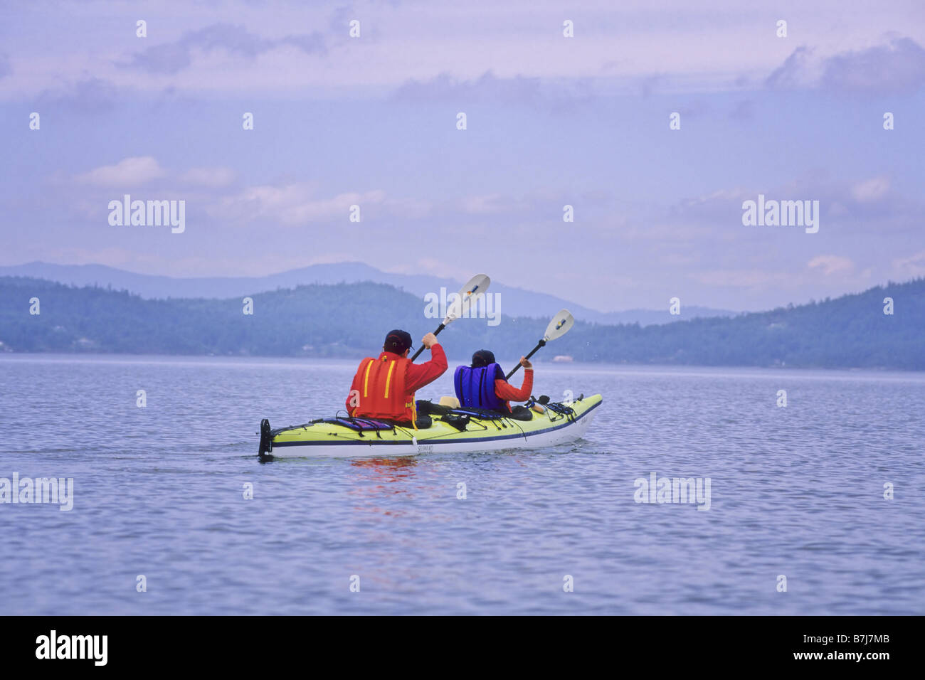 Dad and son paddle in double kayak, near Mayne Island, BC Stock Photo