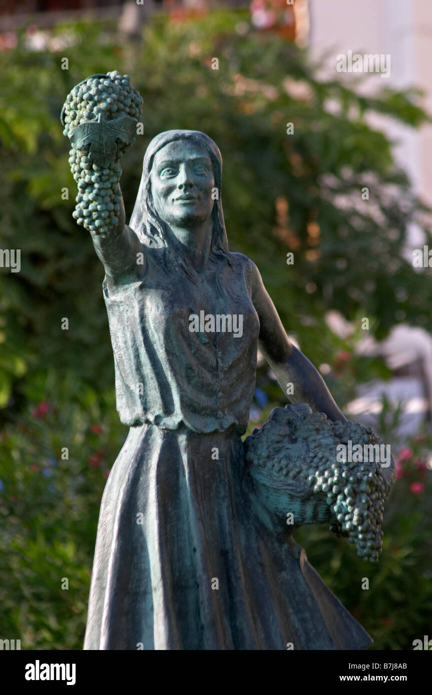 Statue of a girl holding a bunch of grapes and a basket by R Cuello