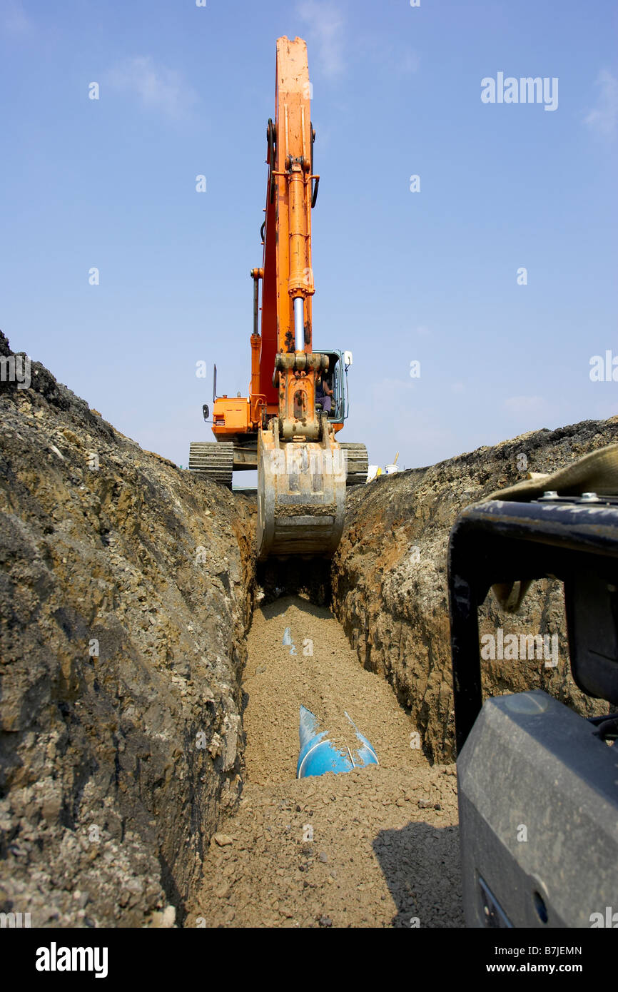 Excavator filling in section of drainage pipe with dirt; Canada