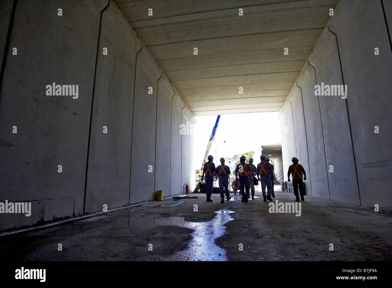Workers walking down a concrete tunnel; Canada, Ontario, Hamilton