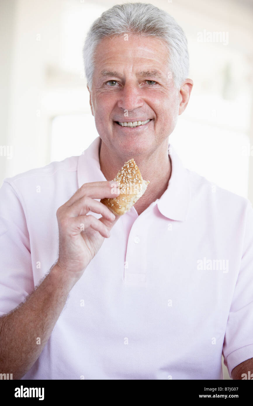 Middle Aged Man Eating Brown Bread Roll Stock Photo