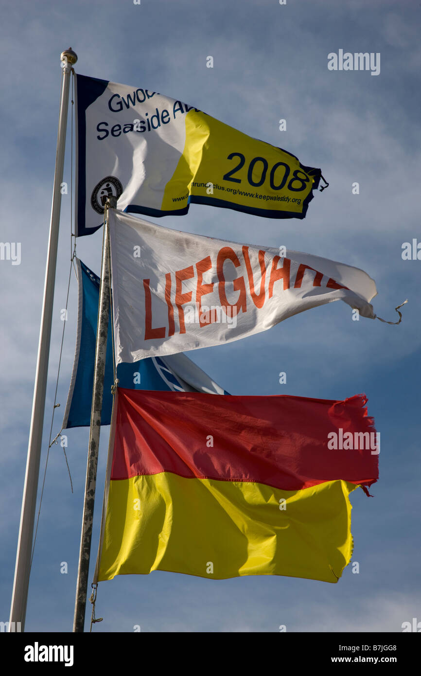 Lifeguard flags and Blue Flag water quality award flying over the beach in Port Eynon Gower Stock Photo
