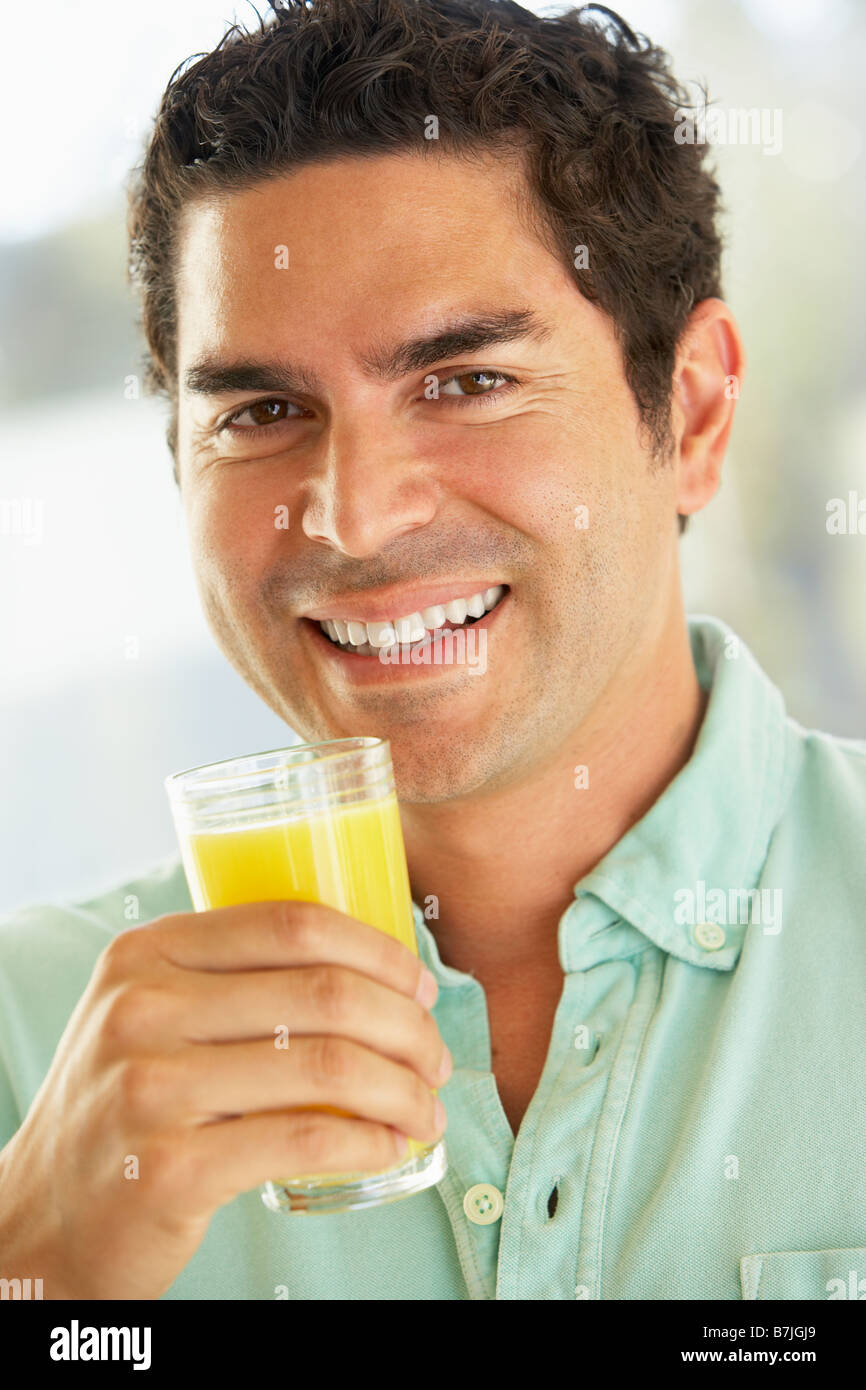 Mid Adult Man Holding A Glass Of Fresh Orange Juice, Smiling At The Camera Stock Photo