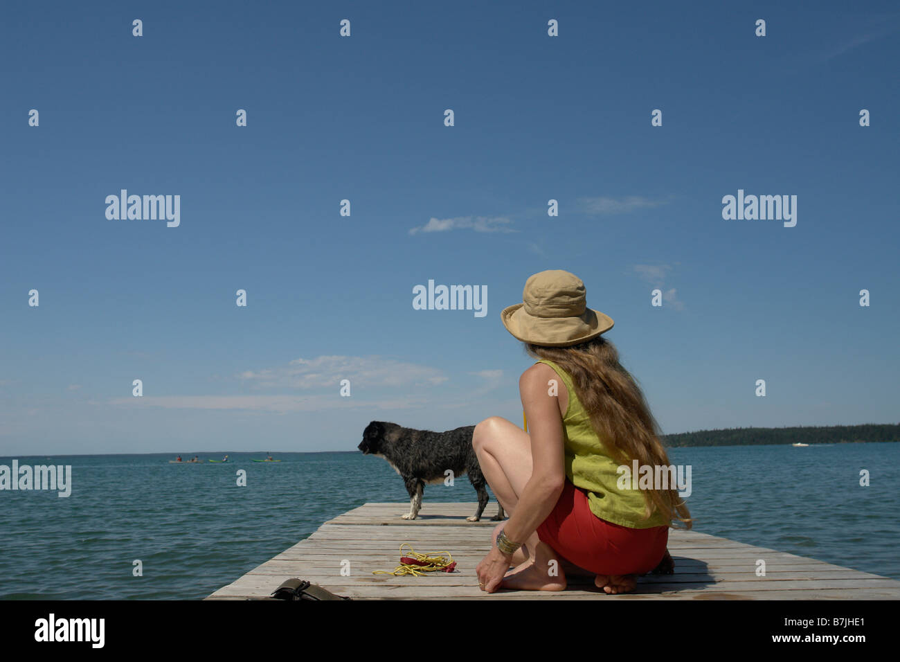Woman and dog on dock, Clear Lake; Canada, Manitoba, Riding Mountain National Park Stock Photo