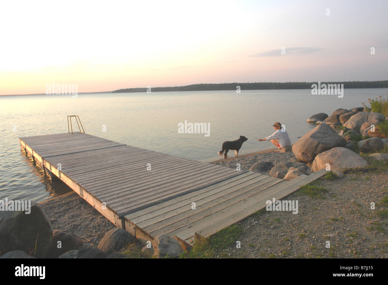 Woman with dog at beach Clear Lake; Canada, Manitoba, Riding Mountain