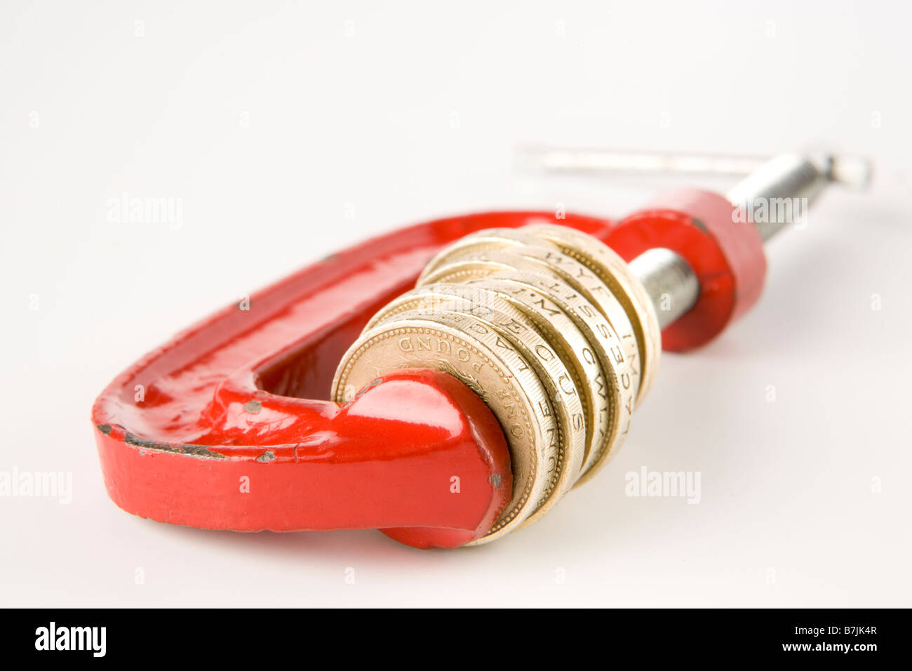 Stack Of Pound Coins In Red Clamp On White Background Stock Photo