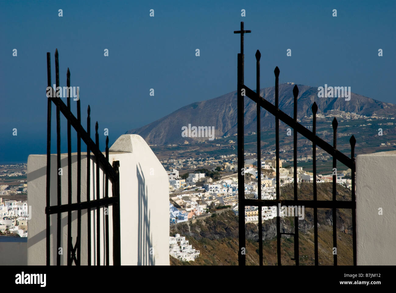 Greece, Santorini, Imerovigli. View through the church gates over the clifftop village of Imerovigli. Stock Photo