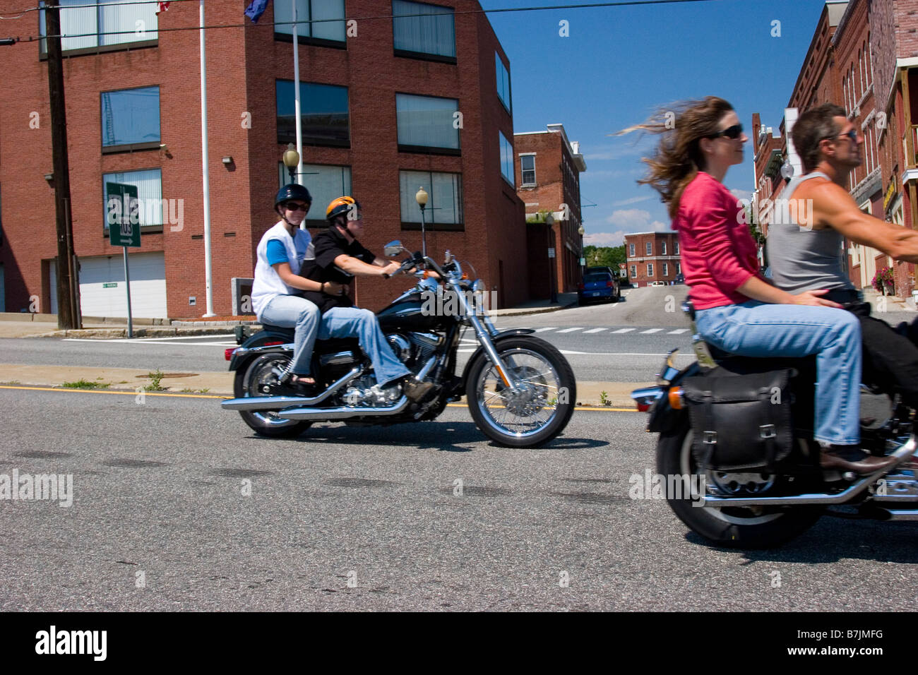 Two couples ride motorcycles through town on a sunny summer day Stock Photo
