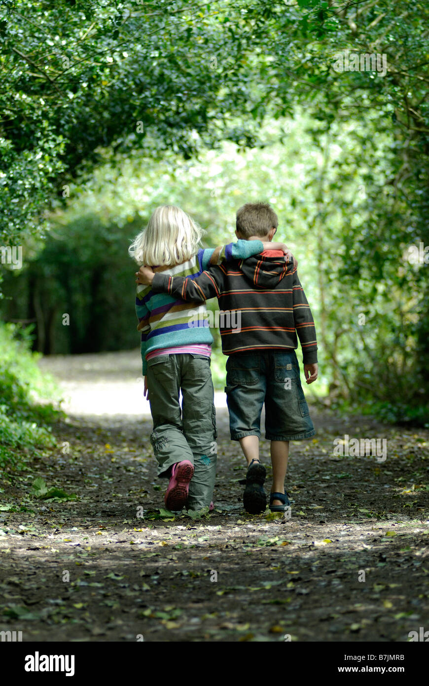 Two Children Walking Arm In Arm In A Wood Stock Photo Alamy