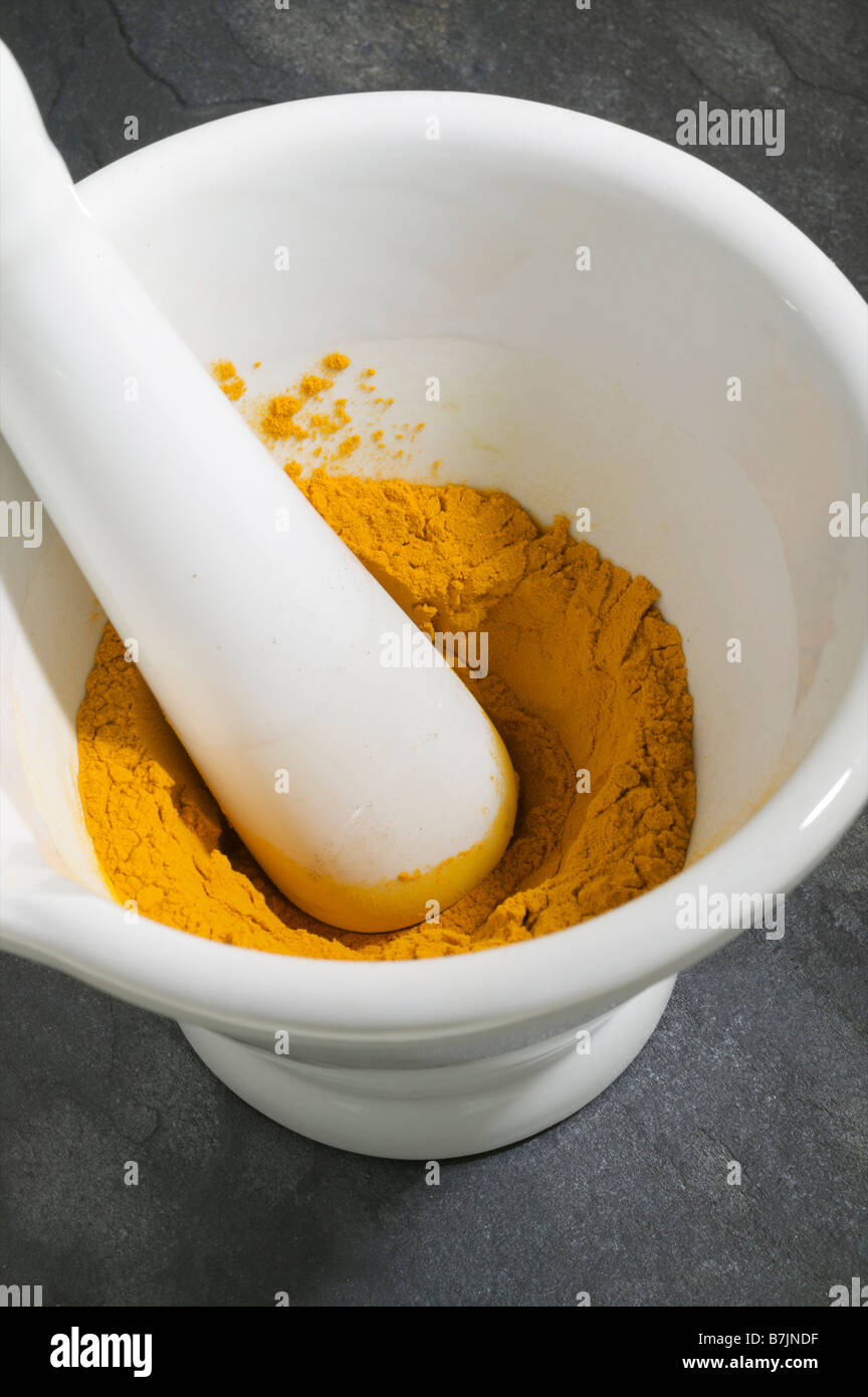 Ground Turmeric spice powder ingredient for Indian food in pestle and