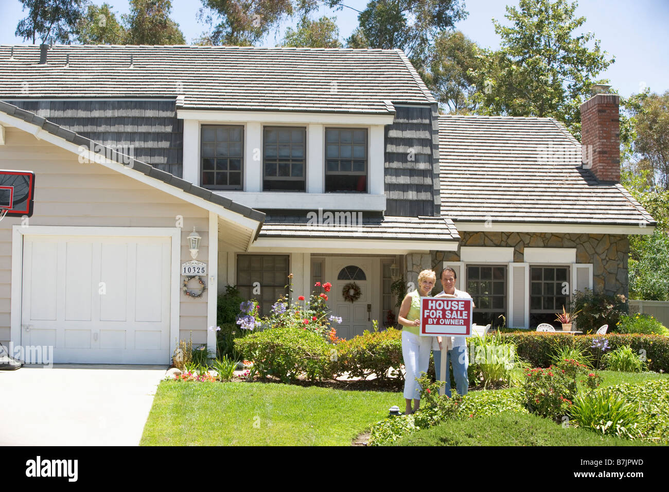 Couple Standing Outside House With Real Estate Sign Stock Photo - Alamy