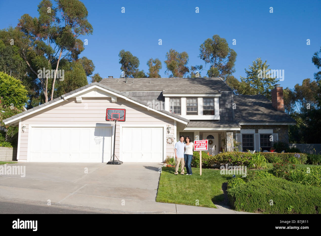 Couple Standing Outside House With Real Estate Sign Stock Photo - Alamy
