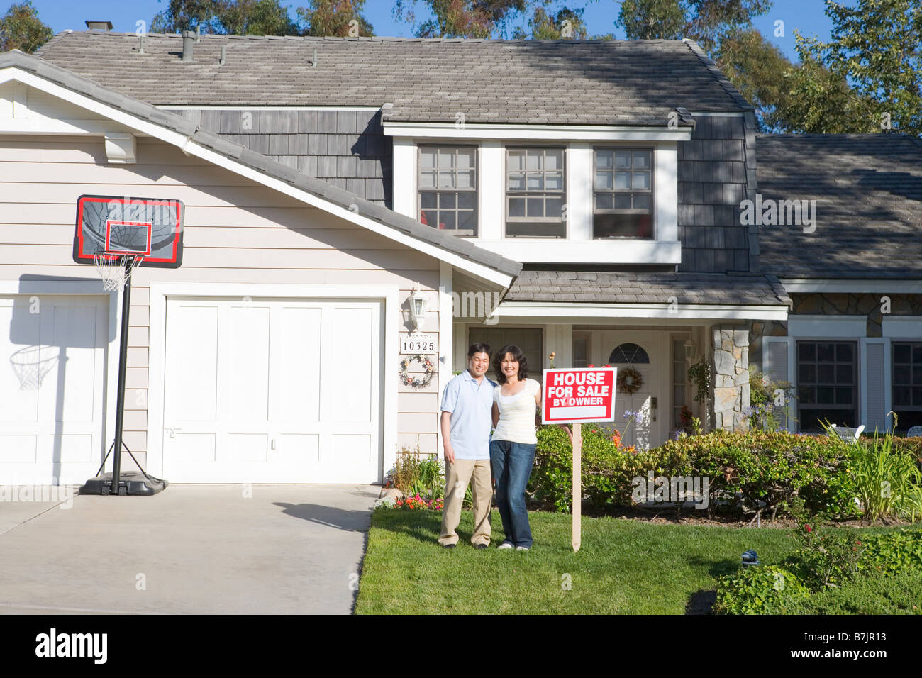 Couple Standing Outside House With Real Estate Sign Stock Photo - Alamy