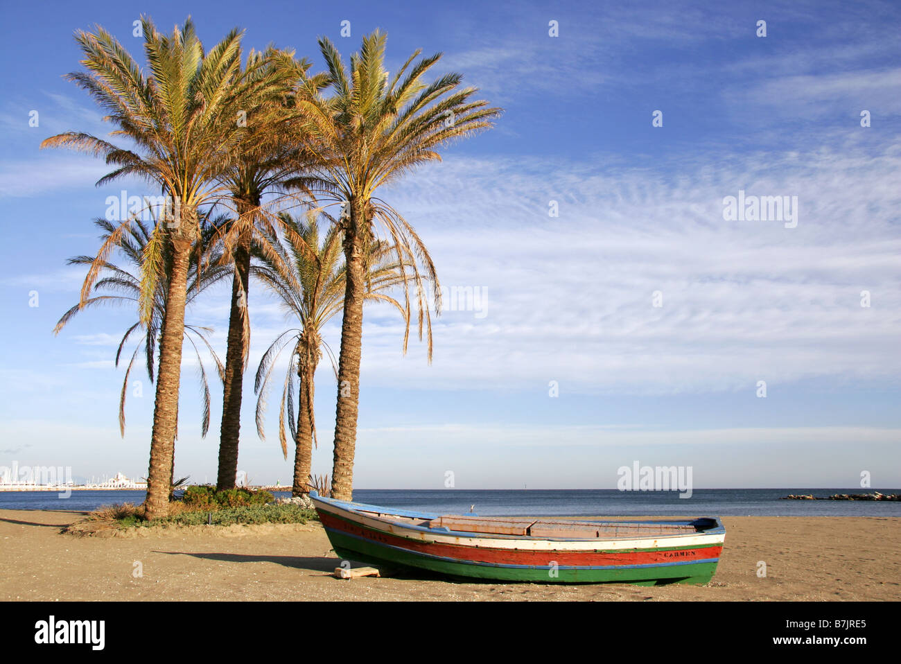 Wooden boat and palm trees on the beach at Benalmadina Costa Del Sol Malaga Andalucia Spain Stock Photo