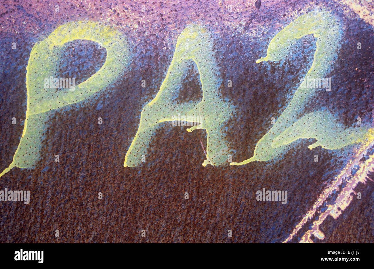 Detail of side of metal tank heavily pitted with rust with PA2 painted onto it with yellow spray which has run Stock Photo