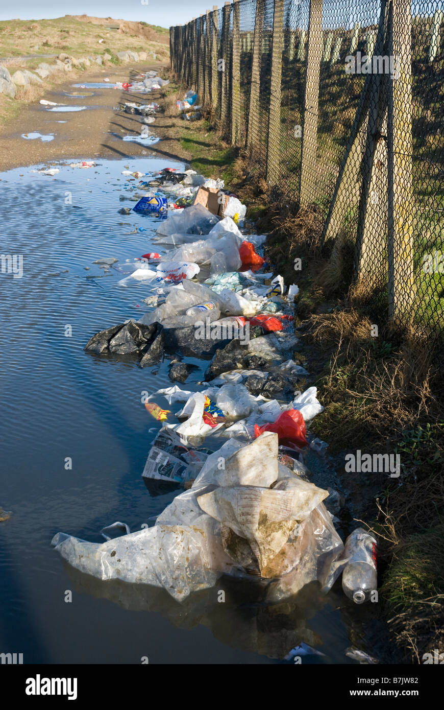 Rubbish outside perimeter fence of landfill site. Stock Photo