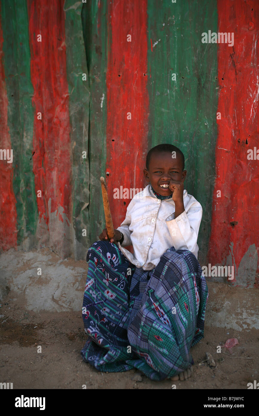 Young boy sitting in front of a brightly painted tin wall Mohammed Haybe IDP Camp Hargeisa Somaliland Stock Photo