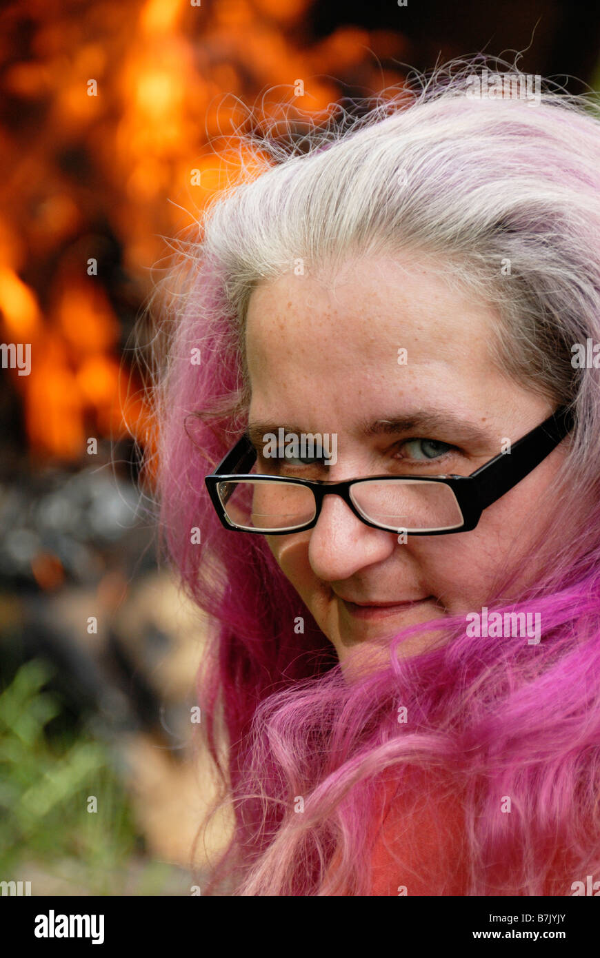 Elderly woman with grey and purple hair in front of fire Stock Photo ...