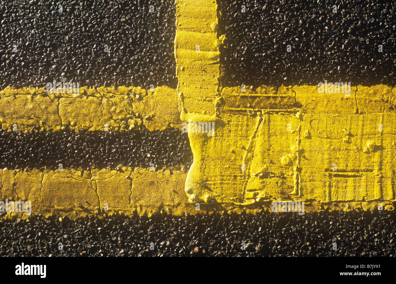 Detail from above of bright double yellow lines on road edge with additional yellow paint thickly applied to create box Stock Photo