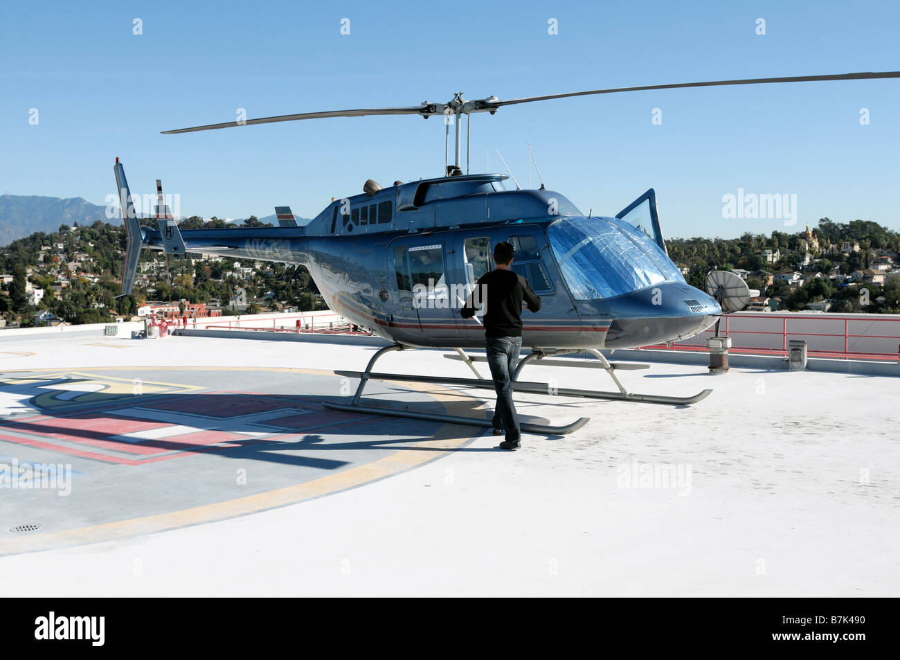 pilot approaching helicopter on top of a downtown los angeles LA take off landing site california Stock Photo