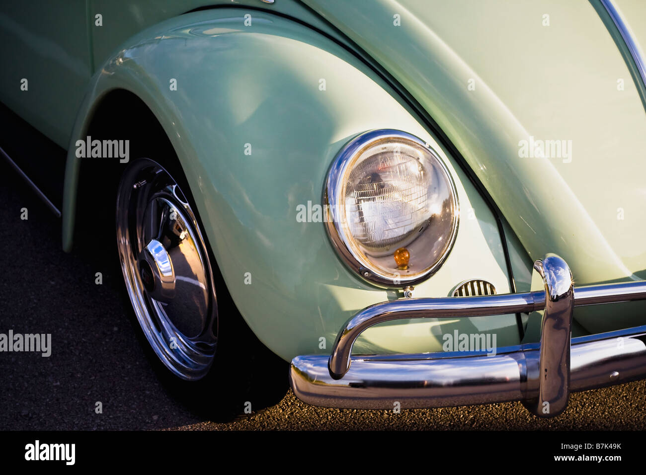 Front end of a vintage VW beetle painted a soft minty green sitting in the evening sun. Stock Photo