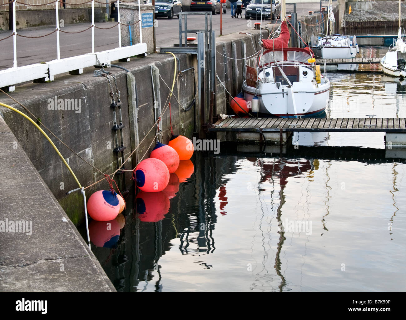 Red buoys out of the water hanging from a wall aboe a quiet bay in Findochty Scotland Stock Photo