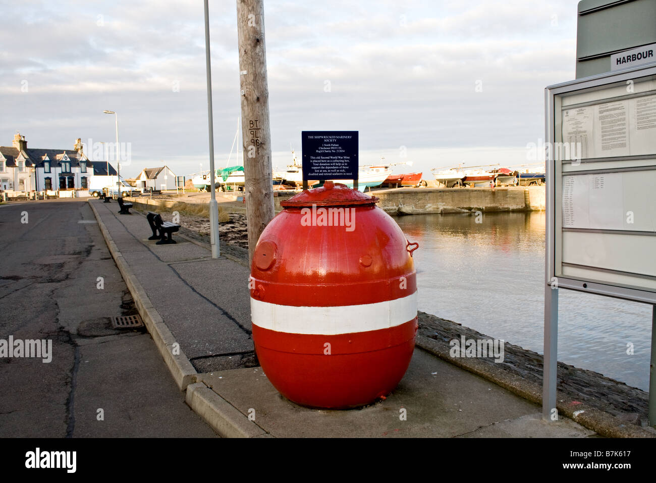 Round red barrell with a white stripe around the middle advertising a fisherman's relief charity in Findochty Scotland Stock Photo