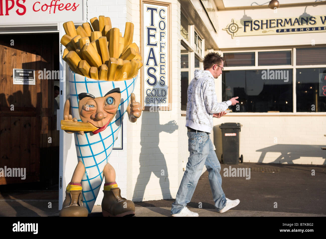 Young man walking away from chip shop Stock Photo
