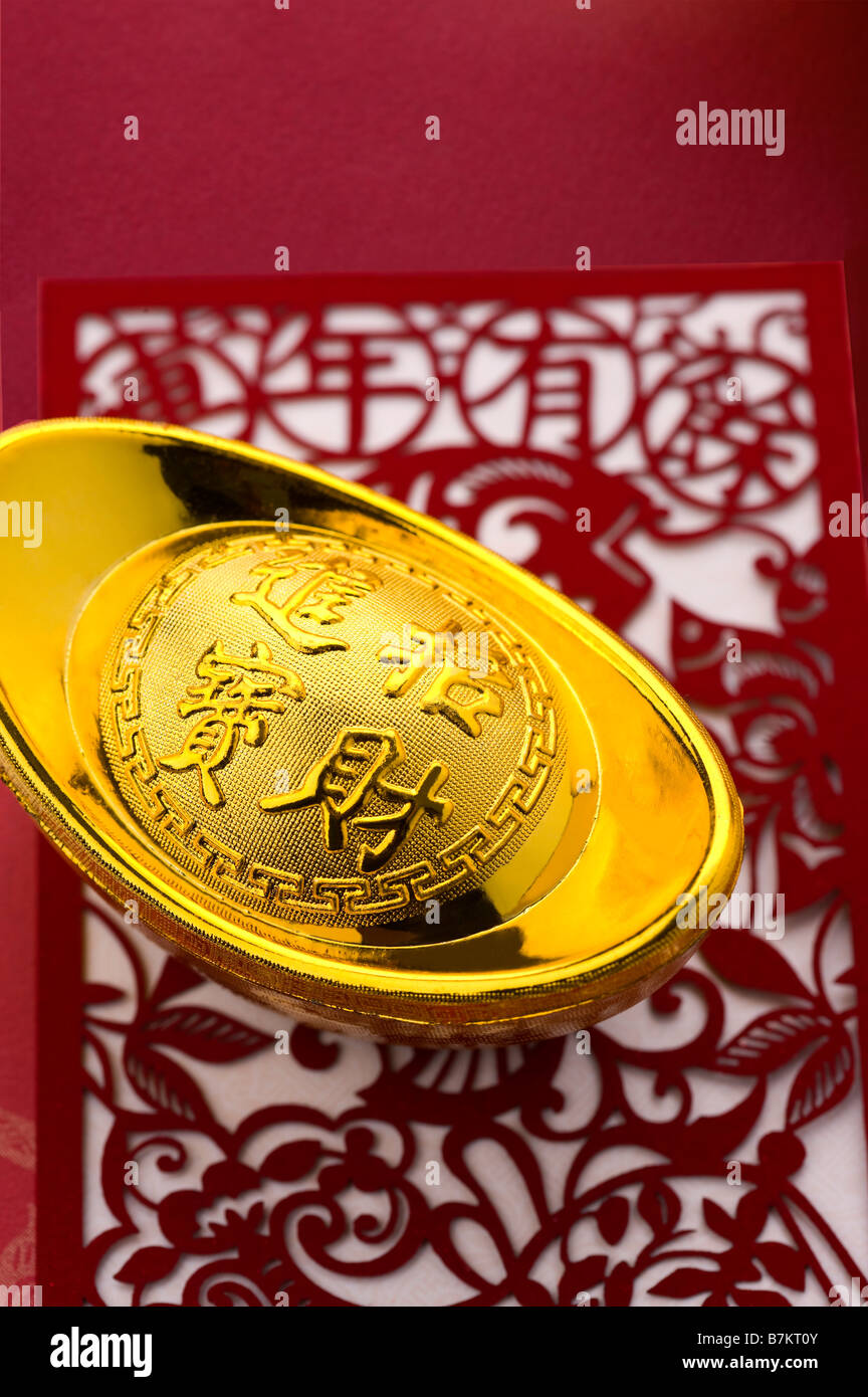 Close-up of a gold ingot on the decoupage with Chinese characters Stock Photo