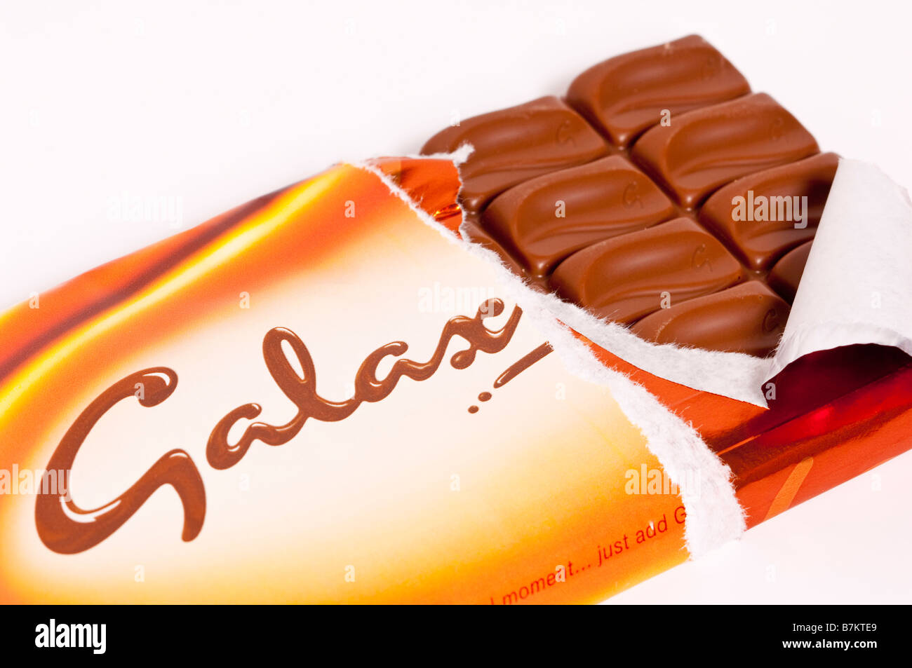A close up of a bar of Galaxy milk chocolate with wrapper opened on a white background Stock Photo