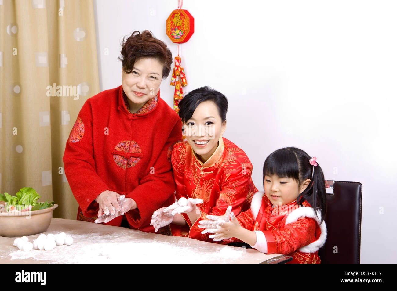 Three generation family in traditional clothes making dumplings together Stock Photo