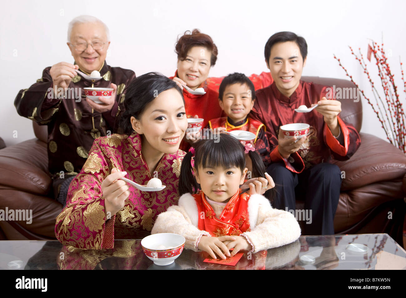 The whole family member in traditional clothing eating stuffed dumpling and smiling at the camera together Stock Photo