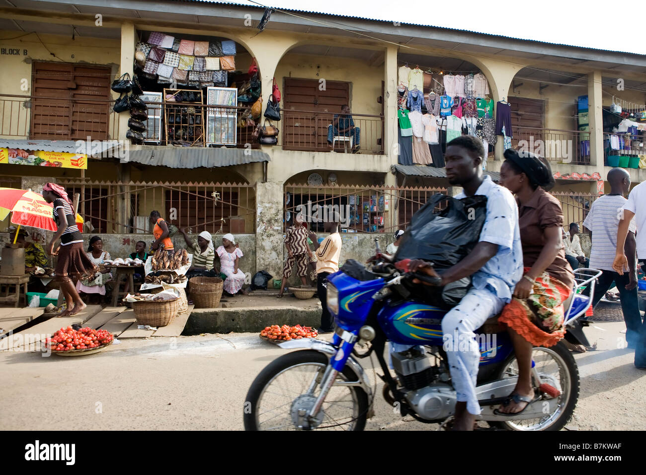 A couple on a motorcycle, ride past the shops in Poka, Epe, Lagos