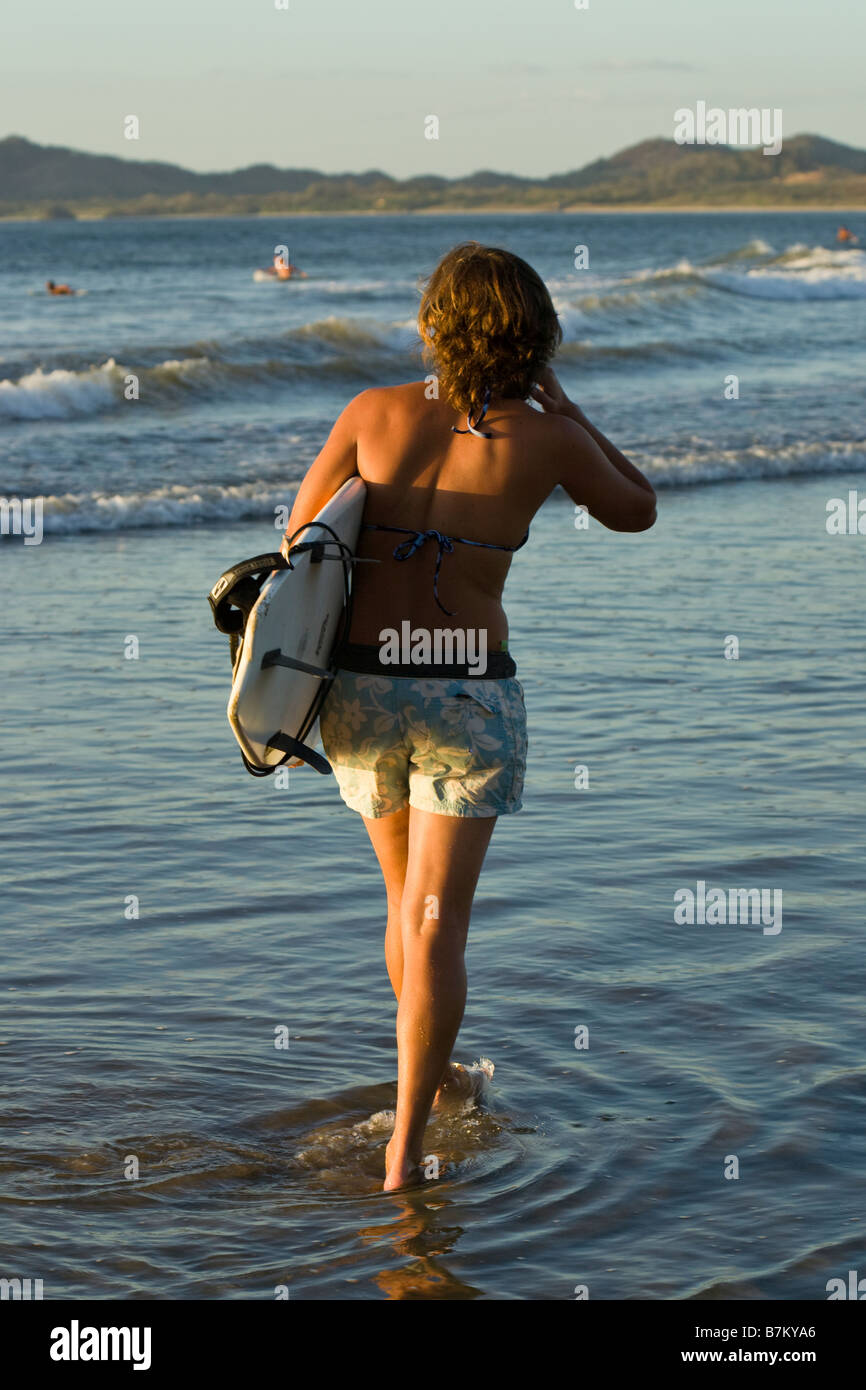 Surfer with surfboard walking on the shore of Playa Tamarindo, Costa Rica. Stock Photo